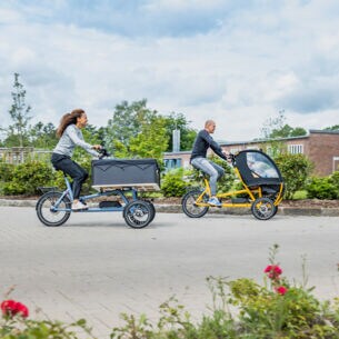 Ein Mann und eine Frau fahren auf zwei Lasten-E-Bikes