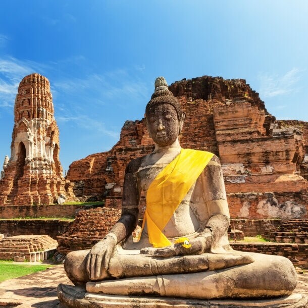 Eine Buddhastatue vor Ruinen eines Tempels