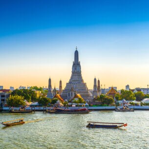Blick vom Wasser auf den Arun Tempel in Bangkok in der Morgendämmerung