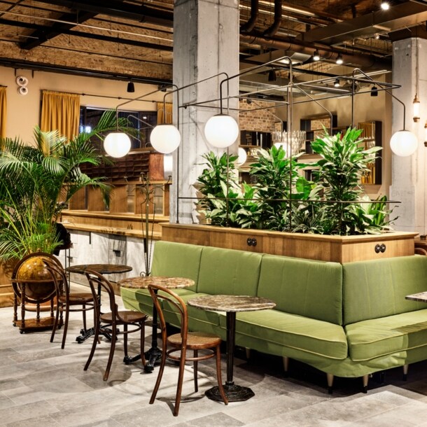 Geräumige Lobby des Berliner Hotels im Telepgraphenamt mit grünem Loungebereich und braunen Designstühlen