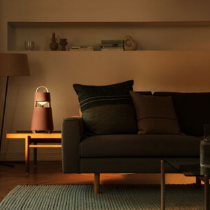 Ein kegelförmiger Bluetooth-Lautsprecher im modernen Design auf einem Tisch neben einer Couch