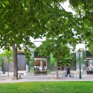 Rendering des Wiener Stadtparks mit Bäumen und Wegen, im Hintergrund ein Restaurant mit offenen Türen und Gästen im Inneren