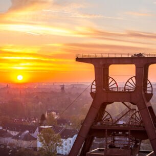 Blick auf Doppelbock-Fördergerüst vom Dach der Kohlenwäsche des UNESCO-Welterbes Zollverein beim Sonnenaufgang