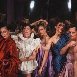 Weibliche und männliche Models posieren während einer Modenschau in glänzenden Kleidern