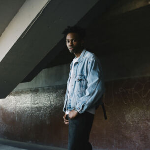 Ein stylischer junger Mann posiert in Jeansjacke in urbaner Umgebung