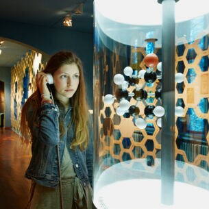 Eine junge Frau steht im Deutschen Technikmuseum in Berlin vor dem Modell eines Moleküls