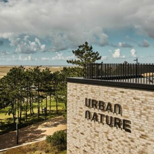 Blick auf die Dachterrasse des Urban Nature Hotels St. Peter Ording, im Hintergrund Bäume, Dünen, Meer und Wolken