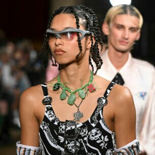 Nahaufnahme eines Models in extravaganter Kleidung und futuristischer Sonnenbrille bei einer Modenschau