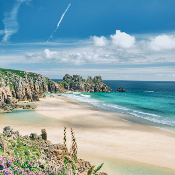 Blick auf die Küste von Cornwall mit Sandstrand, kristallblauem Wasser und Felsvorsprüngen