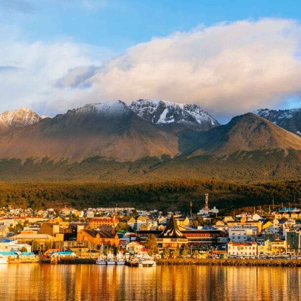 Stadtpanorama von Ushuaia am Wasser vor Bergkulisse im Sonnenuntergang