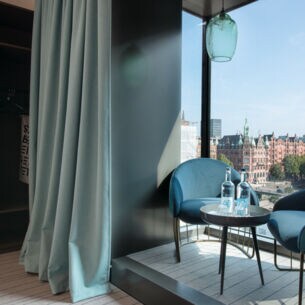 Zwei Sessel stehen in einem Erker, dahinter erstreckt sich Hamburgs Speicherstadt