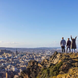 Drei Personen stehen auf einer Erhöhung und blicken von dort über Edinburgh