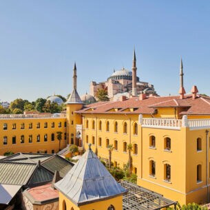Ein gelbes, neoklassizistisches Gebäude mit Innenhof und einer Moschee im Hintergrund