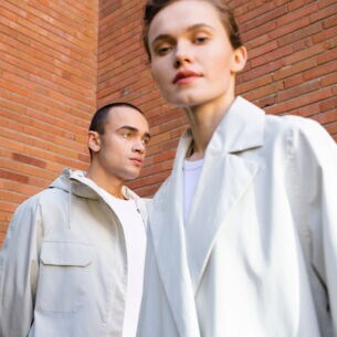 Mann und Frau in weißer Kleidung vor einer Rotklinkerwand.