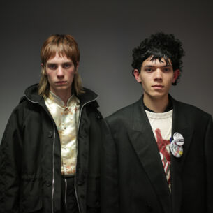 Zwei männliche Models posieren mit schwarzen Jacken und rockigen Stufenhaarschnitten