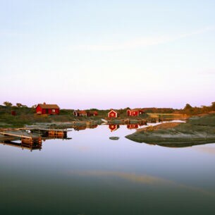 Blick auf rote Holzhäuser auf einer Insel in Schweden