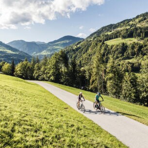Zwei Menschen auf Rädern fahren über den Tauernradweg Alpe Adria