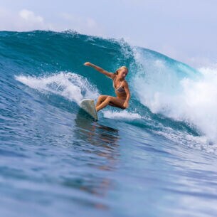 Eine junge Surferin im Bikini reitet auf einer großen Welle