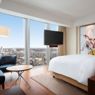 Eine moderne, helle Hotelsuite mit bodentiefen Fenstern und Panoramablick auf Frankfurt am Main