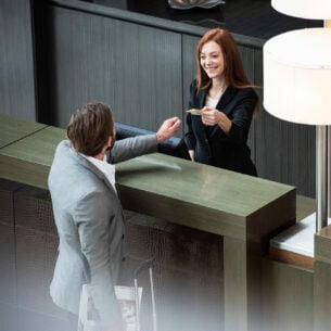 Ein Geschäftsmann hinterlegt eine Kreditkarte bei einer Rezeptionistin beim Einchecken im Hotel