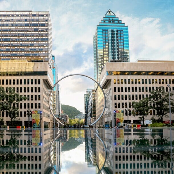 Hochhäuser vor einer Wasserfläche, in der Mitte ein großer Ring
