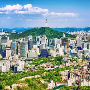 : Stadtpanorama von Seoul mit Hochhäusern, Stadtmauer und einem Fernsehturm auf einem Berg im Zentrum