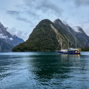 Ein Schiff vor einem Bergmassiv in Neuseeland