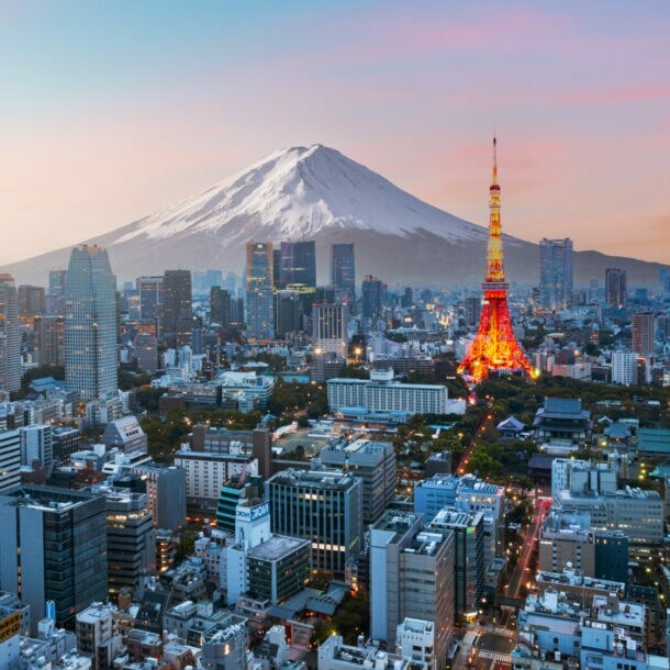 Skyline von Tokio mit beleuchtetem Fernsehturm vor schneebedecktem Fuji in der Abenddämmerung