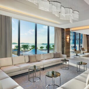 Elegantes Hotelfoyer mit hellen Polstermöbeln und bodentiefen Panoramafenstern mit Blick aufs Meer