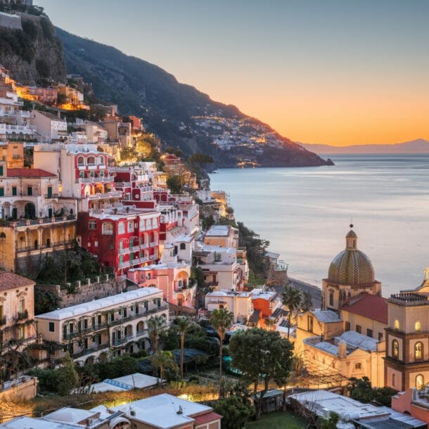 Das Dorf Positano am Hang eines gebirgigen Küstenabschnittes bei Sonnenuntergang
