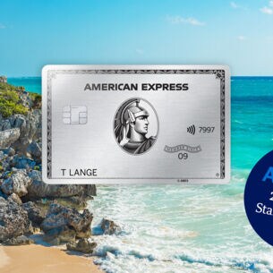 Fotomontage einer silbernen Kreditkarte von American Express vor Strandpanorama mit türkisblauem Wasser und Maya-Ruine auf einem Felsen.