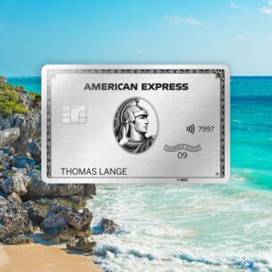 Fotomontage einer silbernen Kreditkarte von American Express vor Strandpanorama mit türkisblauem Wasser und Maya-Ruine auf einem Felsen