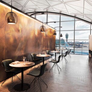 Modernes, edles Restaurant mit eingedeckten Tischen in einem Flughafen mit Panoramablick aufs Rollfeld