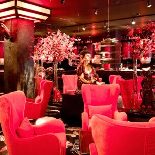 Beleuchtete, elegante Bar mit asiatischem Dekor und pinken Samtseseln.