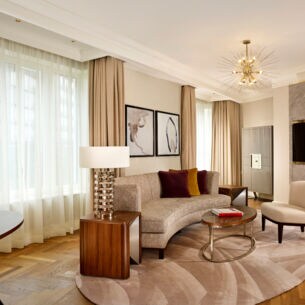 Stilvolle Hotelsuite mit Parkettboden und hellen Polstermöbeln.
