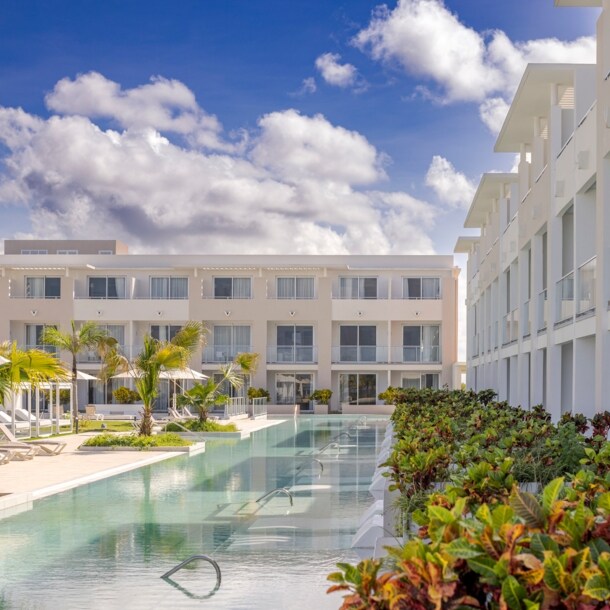 Moderne, dreistöckige Hotelanlage mit begrünter Poollandschaft.