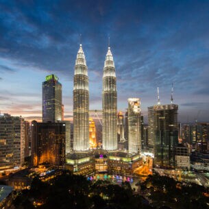 Nachtaufnahme der erleuchteten Skyline der City von Kuala Lumpur mit den Petrona Twin Towers im Mittelpunkt.