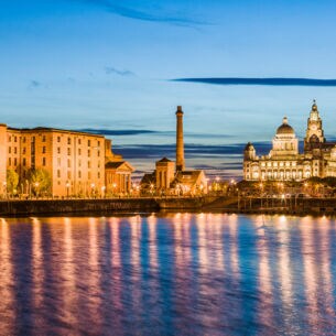 Waterfront in Liverpool bei Nacht mit beleuchteten Gebäuden im Hintergrund.
