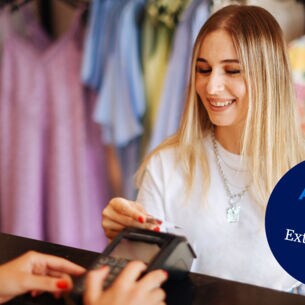 Eine junge Frau bezahlt kontaktlos mit ihrer Kreditkarte an einem Kassentresen in einer Modeboutique