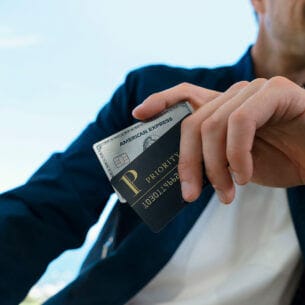 Eine Person hält eine American Express Platinum Kreditkarte mit einer Priority Pass Karte in der Hand.