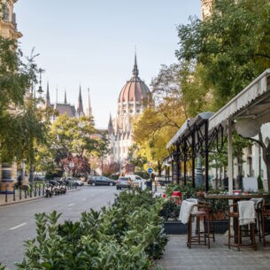 Straßenaufnahme in Budapest mit der Kuppel des Parlamentsgebäudes im Hintergrund. 