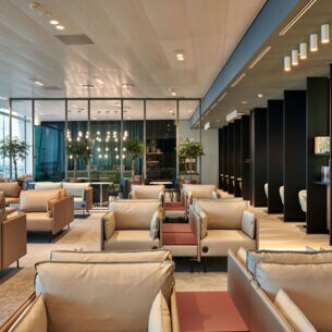 Moderne Flughafenlounge mit Sesseln aus beigem Stoff.