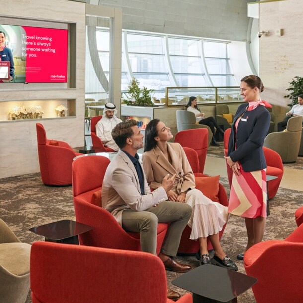 Mehrere Personen sitzen auf Polstermöbeln in einer modernen Flughafenlounge.