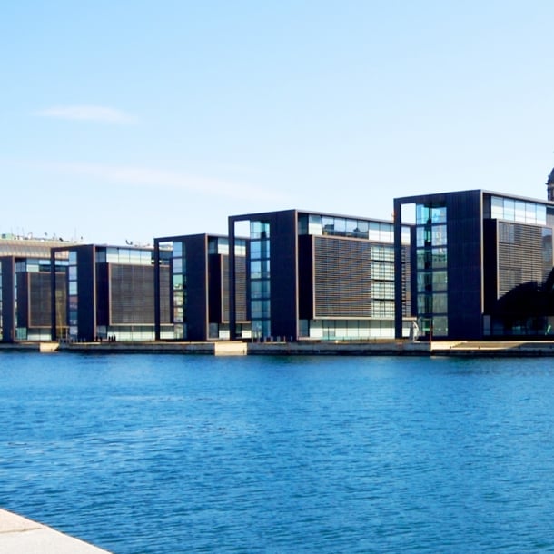 Moderne, kubistische Bürohäuser mit Glasfassaden an einem Kanal.