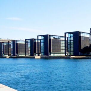 Moderne, kubistische Bürohäuser mit Glasfassaden an einem Kanal.