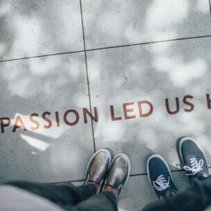 Zwei Personen lesen auf einem Gehweg den Schriftzug "Passion led us here"