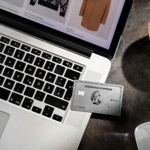 Eine silberne American Express Kreditkarte liegt auf einem Laptop beim Online-Shopping.