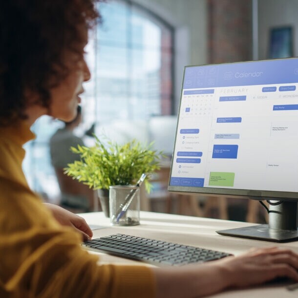 Eine Frau sitzt an ihrem Schreibtisch und arbeitet am Computer.