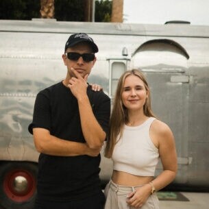 Sarah Emmerich und Benjamin Diedering stehen vor einem Wohnwagen in den USA.