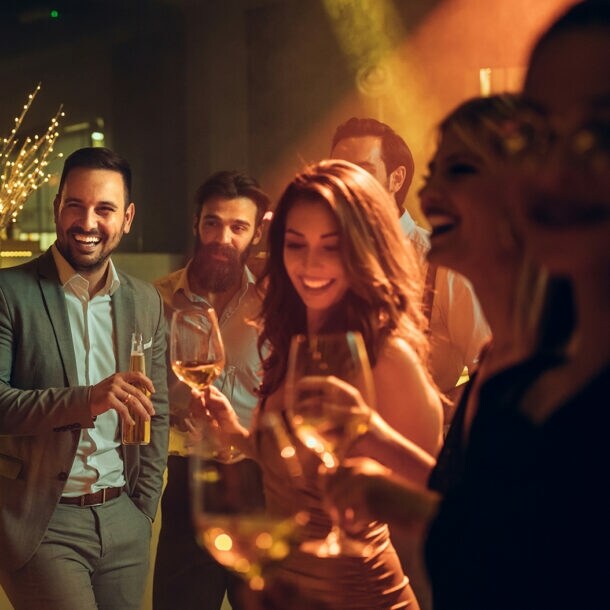 Eine Gruppe elegant gekleideter Frauen und Männer feiert in einem Club.